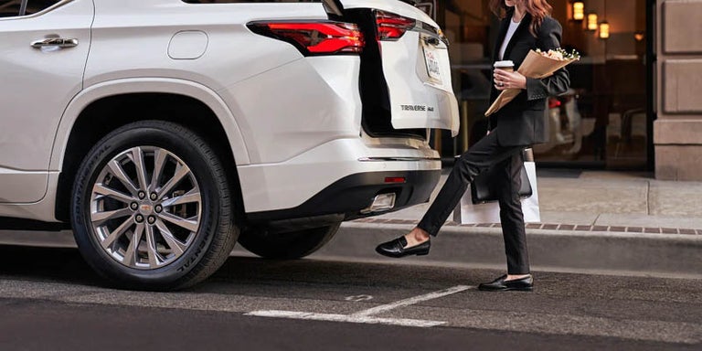 A woman opening the trunk with the available AutoSense Power Liftgate of the 2022 Chevy Traverse